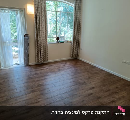 רצפת פרקט עץ כהה בחדר ריק עם חלון גדול